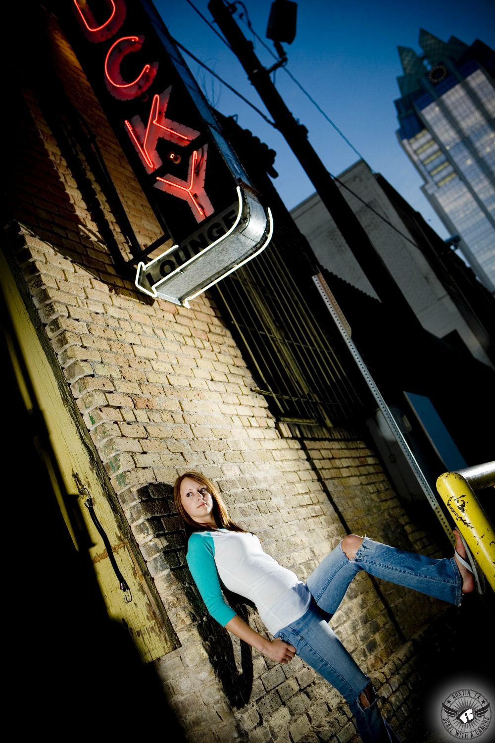 Warehouse district downtown Austin senior portraits of girl in jeans under the Lucky Lounge sign.